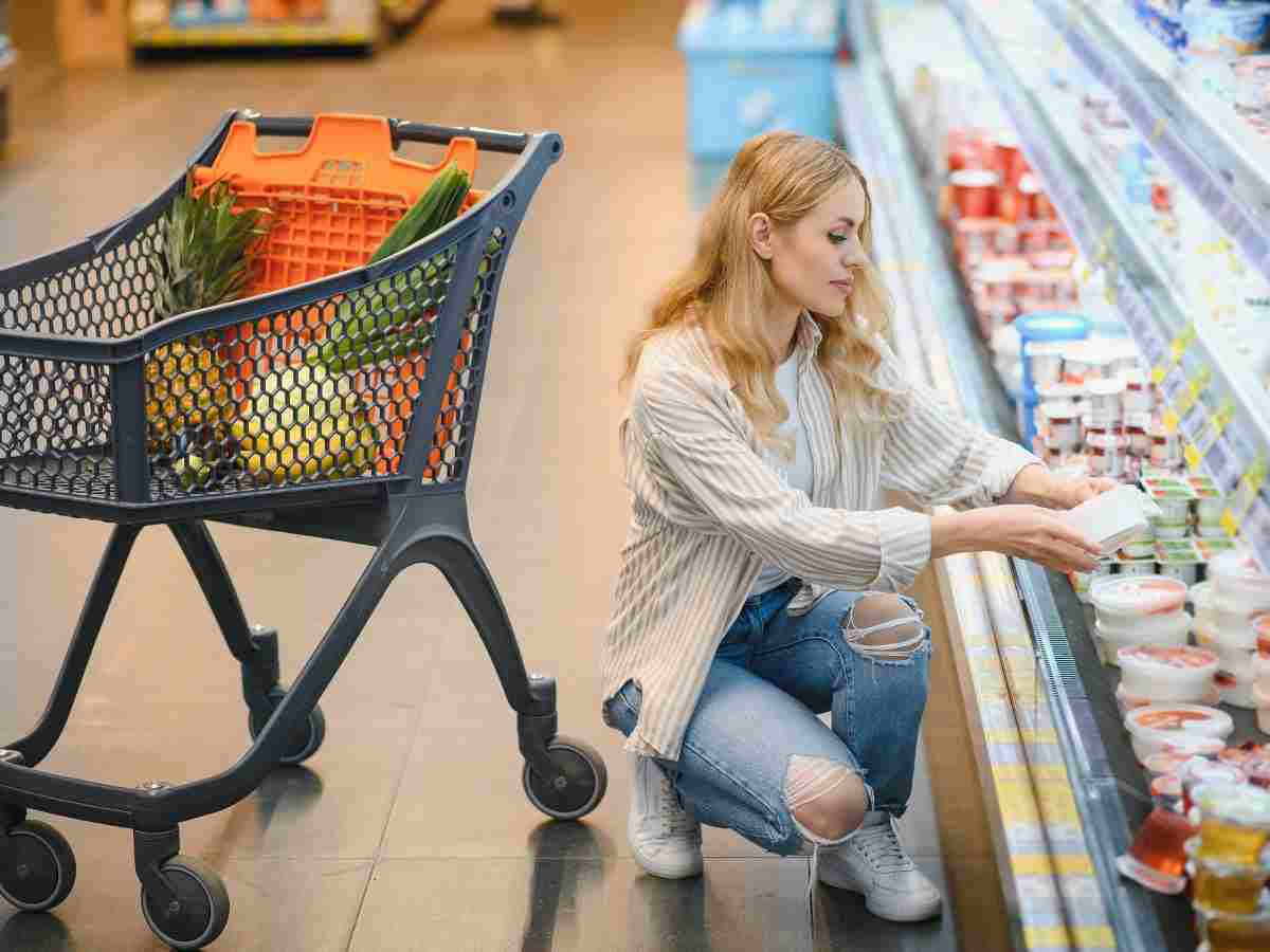 donna chinata che osserva cibo al banco frigo