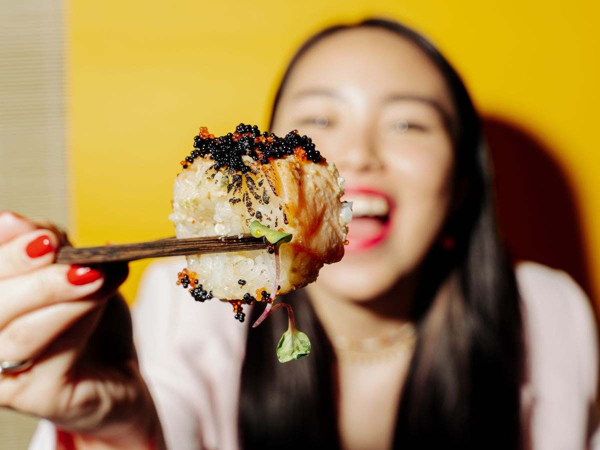 donna tiene pezzo di sushi con bacchette